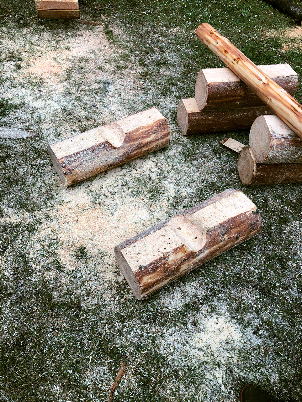 Notches are cut on the two bottom logs of a DIY garden table