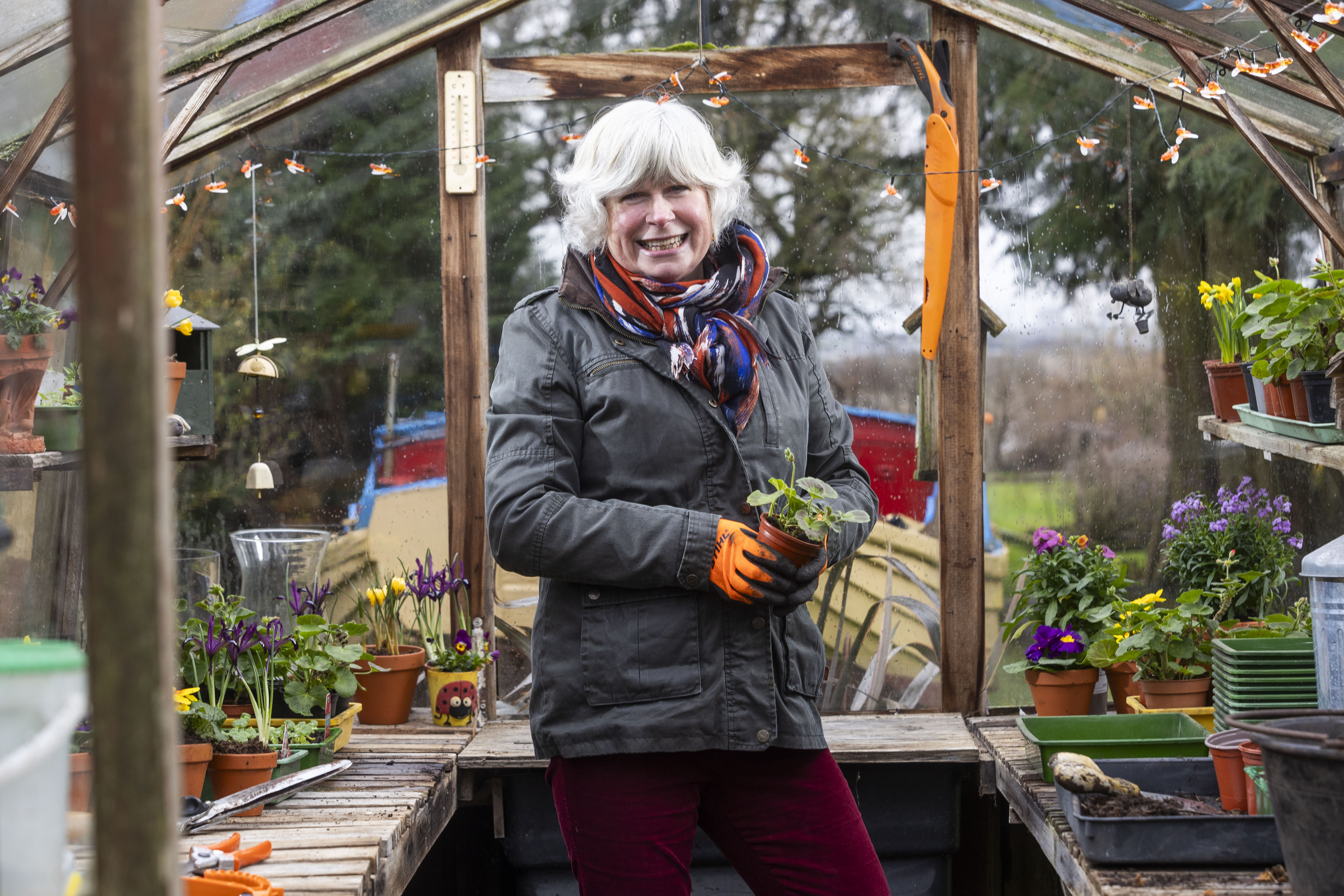 award-winning gardener jane moore holding potted plant in greenhouse