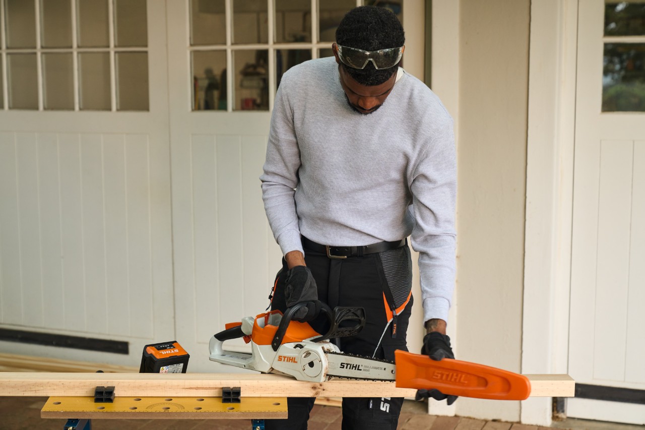 A man in front of a workshop removing the guard from a STIHL MSA 70 cordless chainsaw 