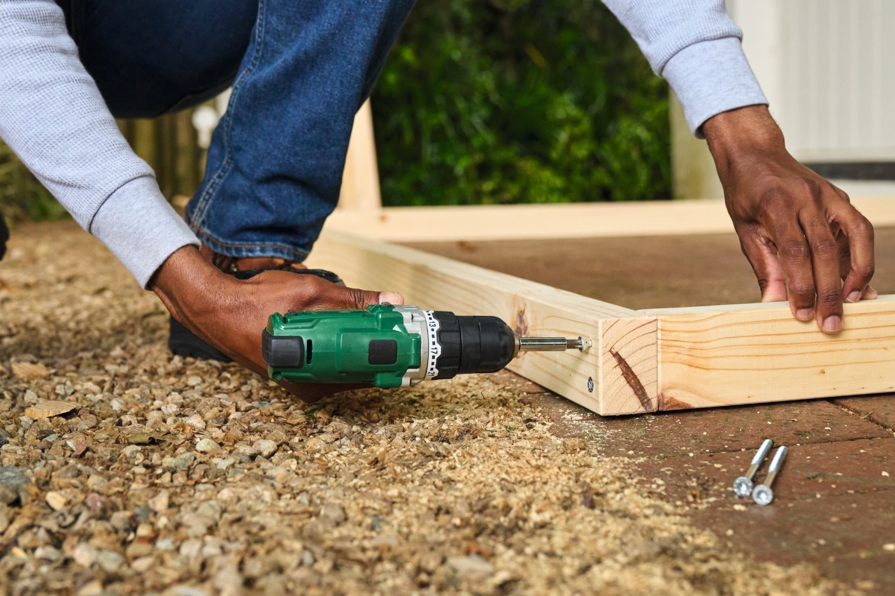 A man pre-drilling holes with the cordless screwdriver for the football goal