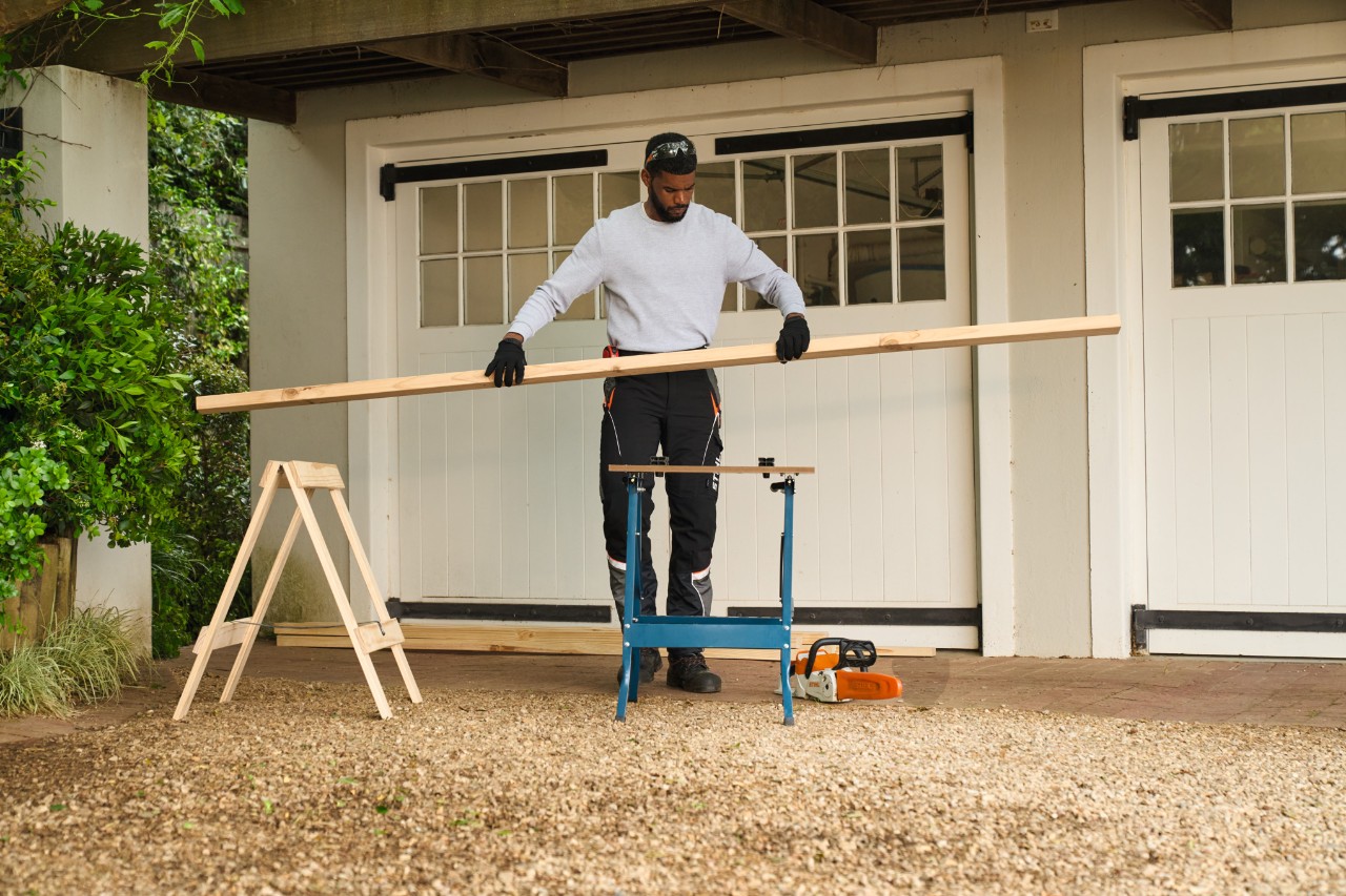 A man placing a piece of square-edge timber on a workbench