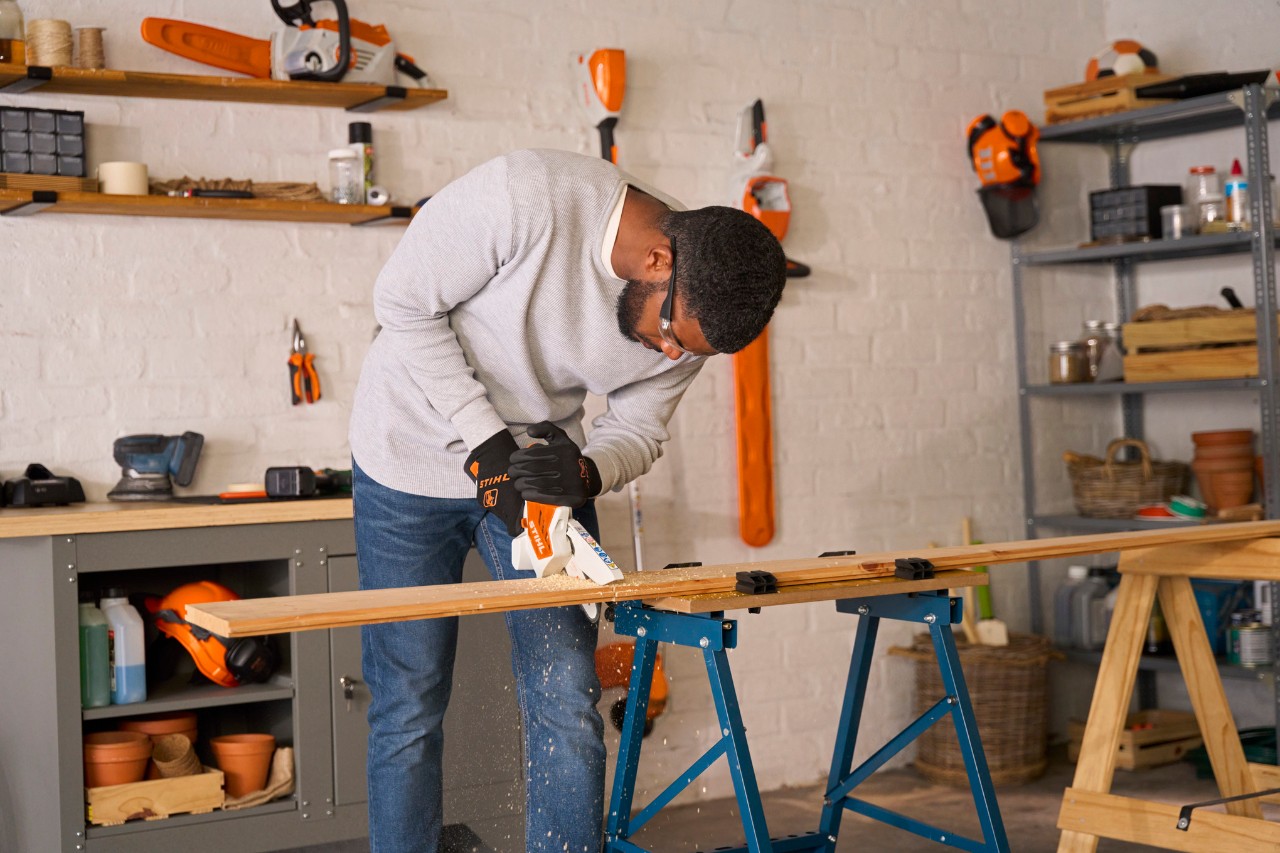 A man measuring a length of wood on a work bench