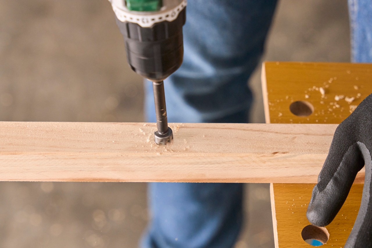 A wood drill is used to make a 15mm hole in the wooden tent pole
