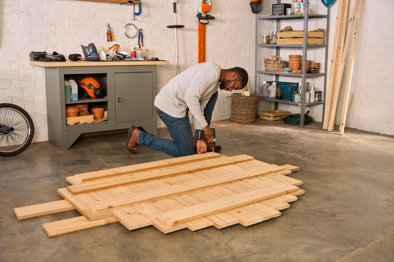 A man screwing the base boards together to secure the floor