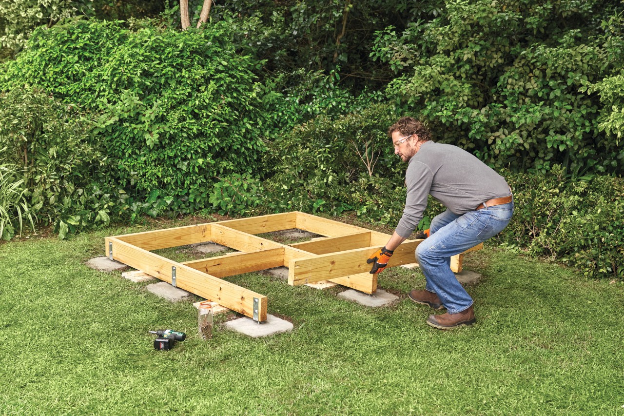 A man building the timber base frame of a diy garden shed