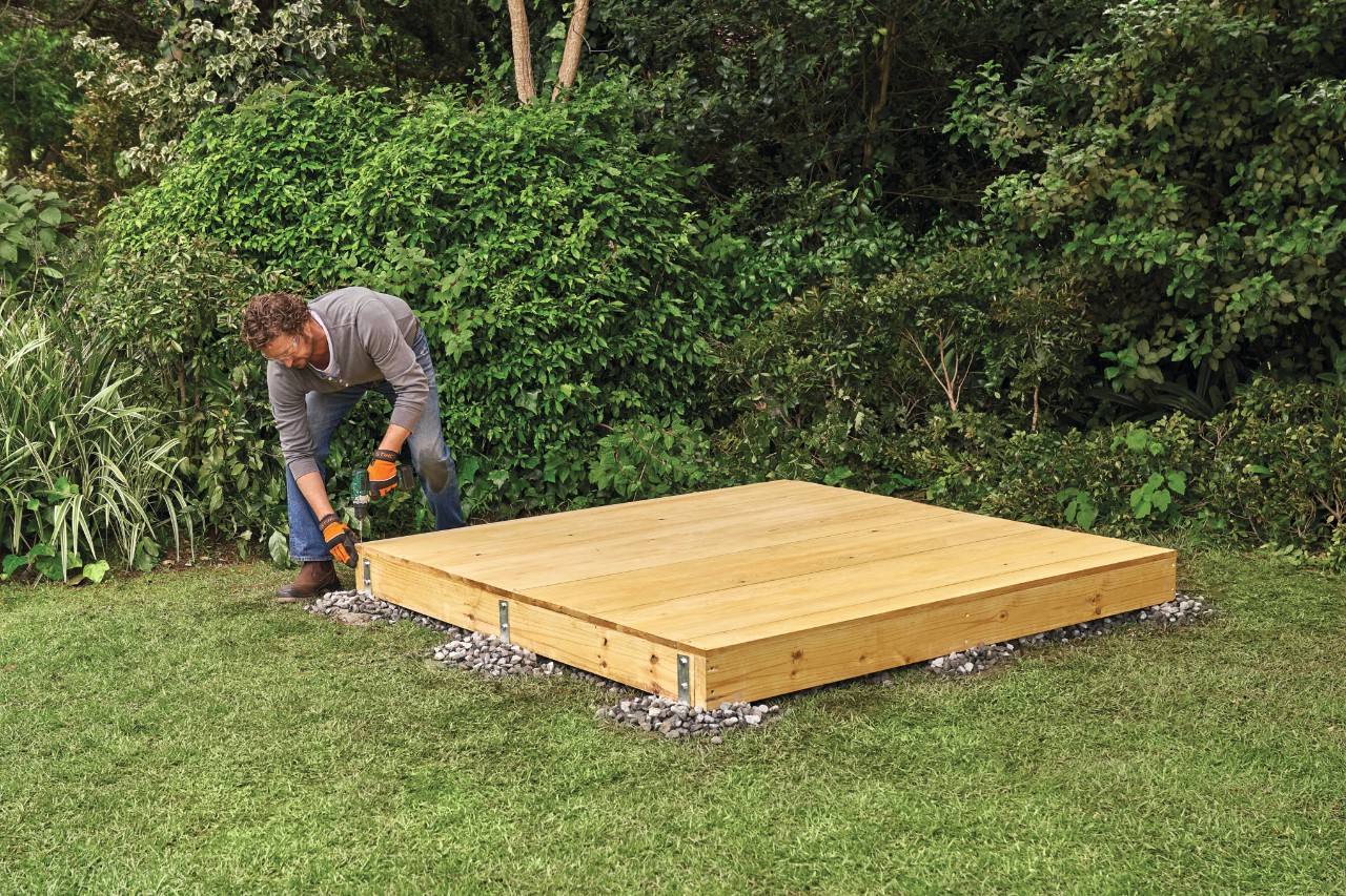 A tongue-and-groove floorboard being screwed to a timber garden shed base