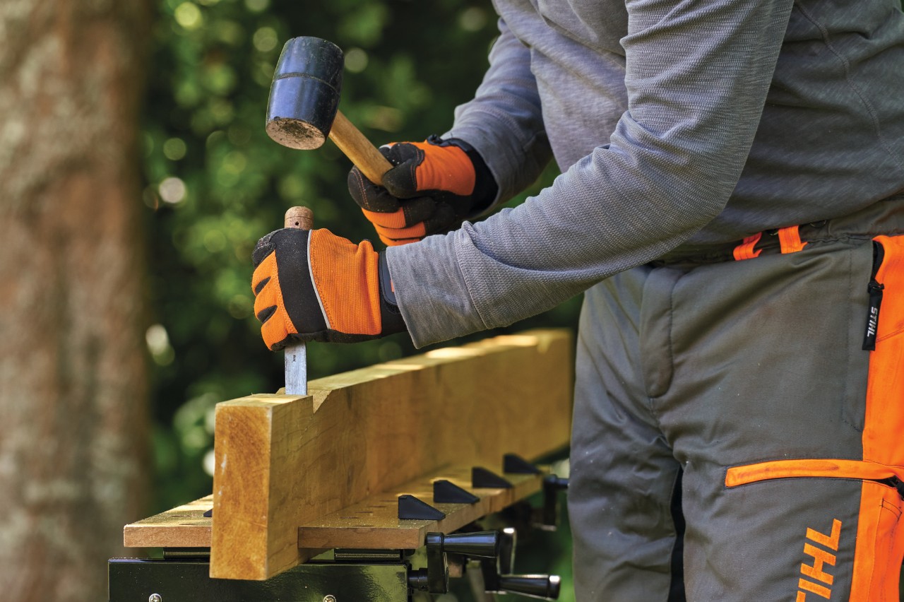 A roof beam being notched with a hammer and chisel