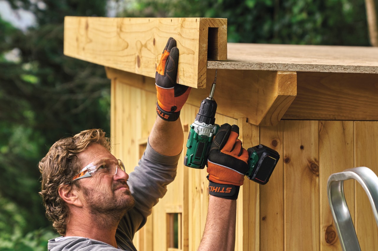 A man mounting a pre-assembled roof edge to a shed roof