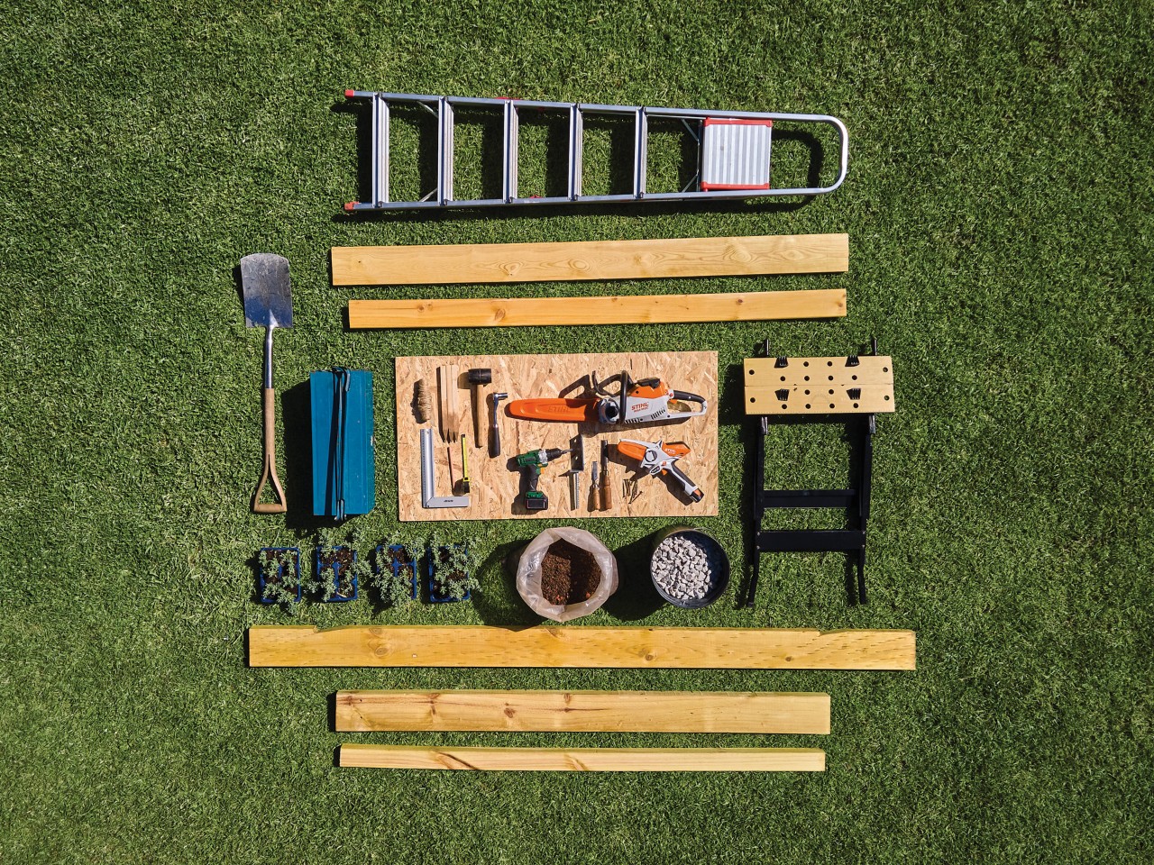 Materials and tools laid out neatly on a green lawn ready to build a garden shed