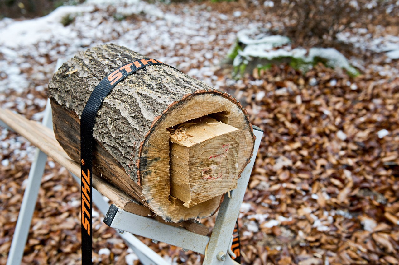 DIY wooden lantern: a cut-down log fixed to a sawhorse with a STIHL tensioning belt, with a square core partly removed