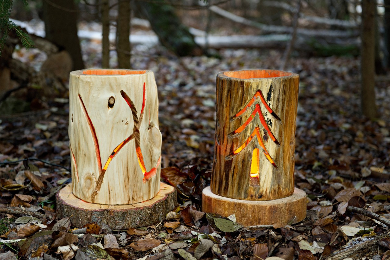 Two luminous DIY log lanterns with unique patterns carved into them