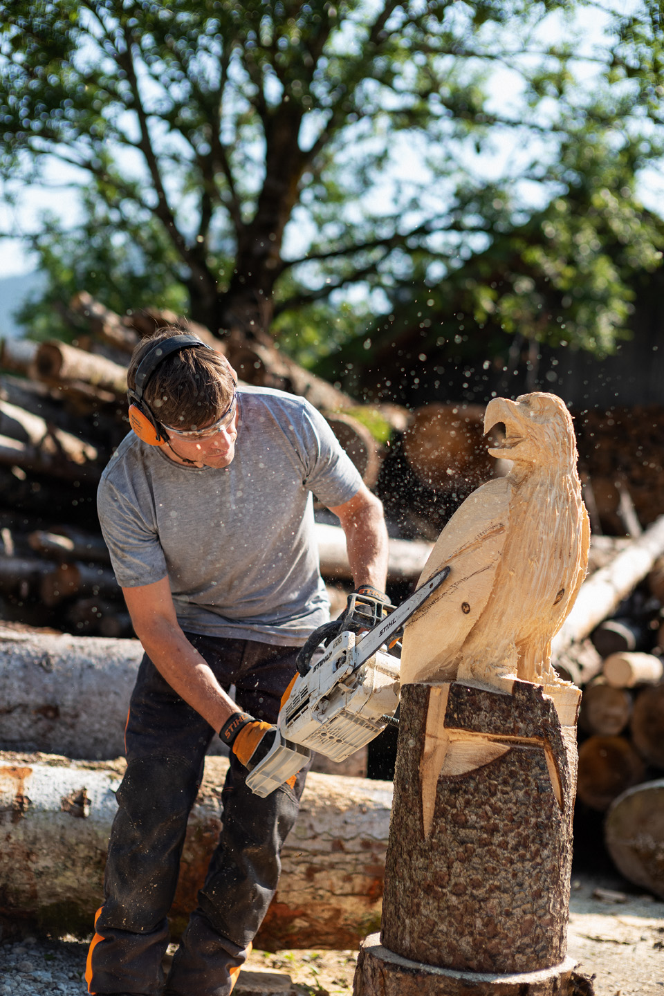 A man making an eagle sculpture from a log using a STIHL MSE 193 CE petrol chainsaw with carving guide bar