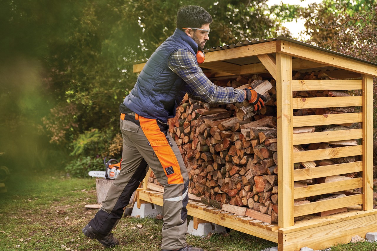 A man stacking firewood in a DIY log store
