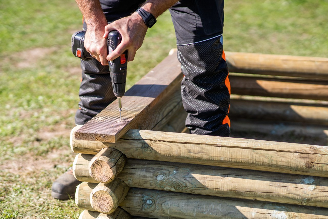 A bench for the DIY sandpit is screwed onto the top stake.