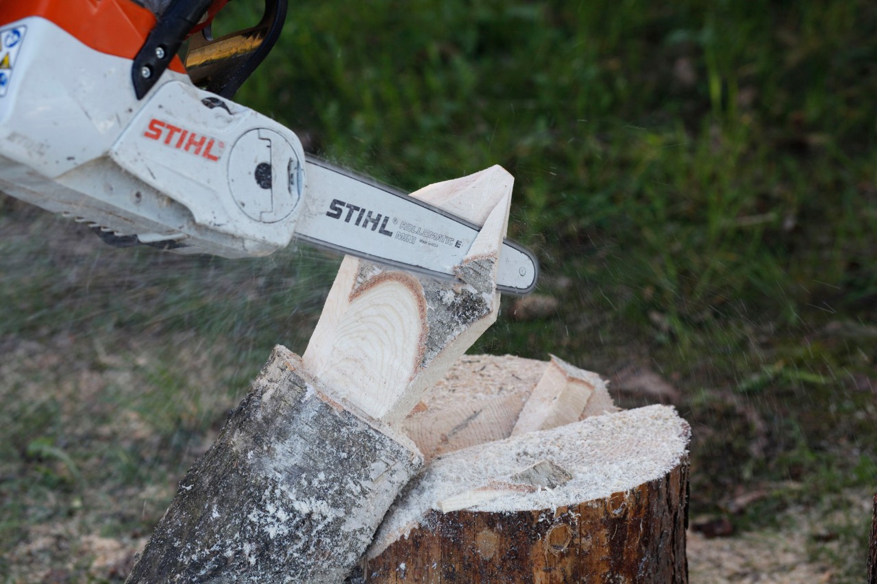 A STIHL MSA 140 C cordless chainsaw being used to add detail to a wooden flame on a log