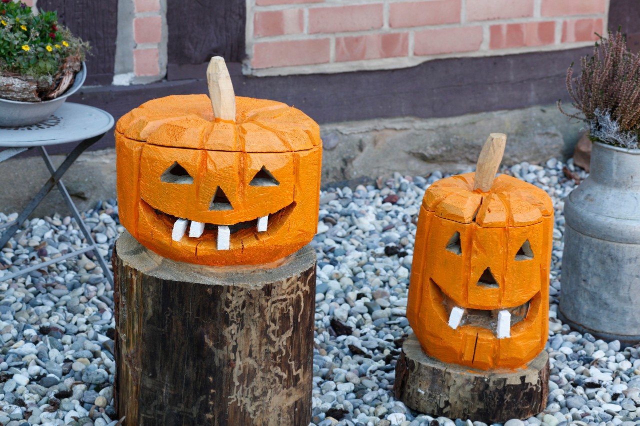 A pair of DIY decorative wooden pumpkins made from logs, outside a house