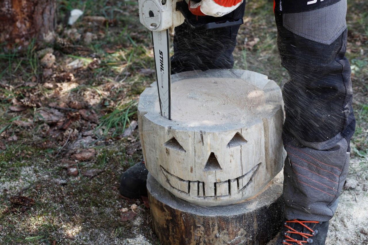 A STIHL MSA 140 C chainsaw being used to cut the centre out of a wooden pumpkin.