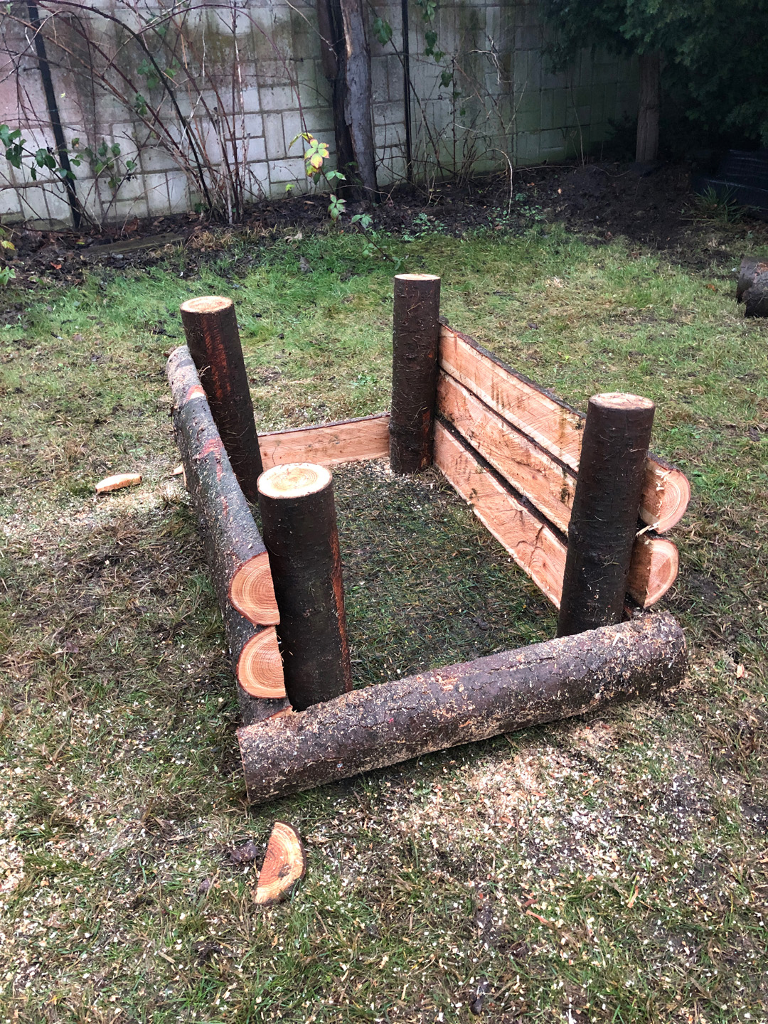 Build a raised bed from logs: side panels are fitted to the four posts