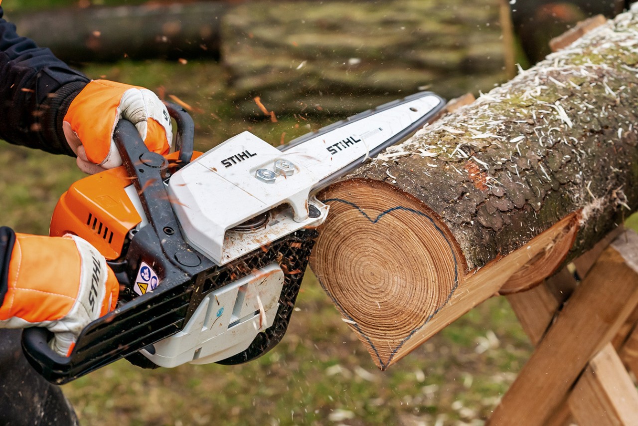 Make flat heart slices from a log: heart shape being carved from wood with a STIHL MS 170 petrol chainsaw