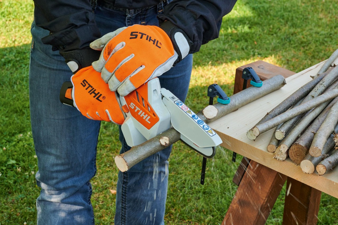 DIY advent wreath: a person wearing protective gloves cuts branches into short pieces using a STIHL GTA 26 Garden pruner