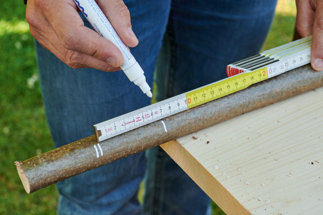 DIY heart ornament from a branch: a branch being measured and marked with a white pen