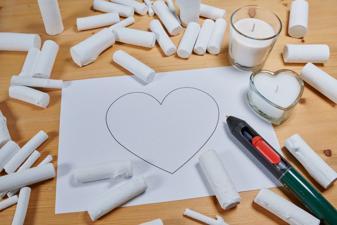Make a heart ornament from a branch: a heart shape on a piece of paper, with painted branch pieces scattered around it