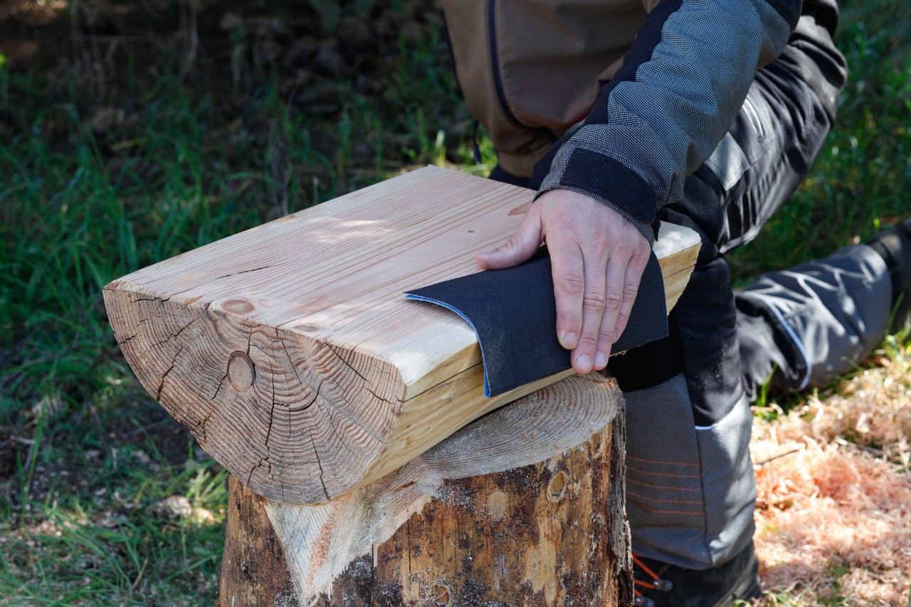 DIY stool with log seat: The sawn surface of a split log being sanded