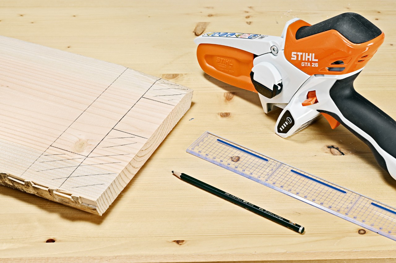 Pencil markings on a wooden plank beside a STIHL GTA 26 cordless garden pruner, pencil and ruler