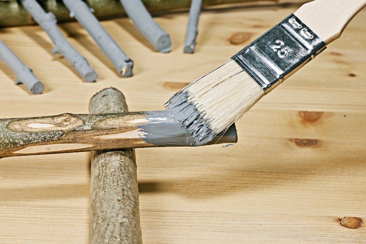 DIY table lamp from twigs: a branch being painted grey