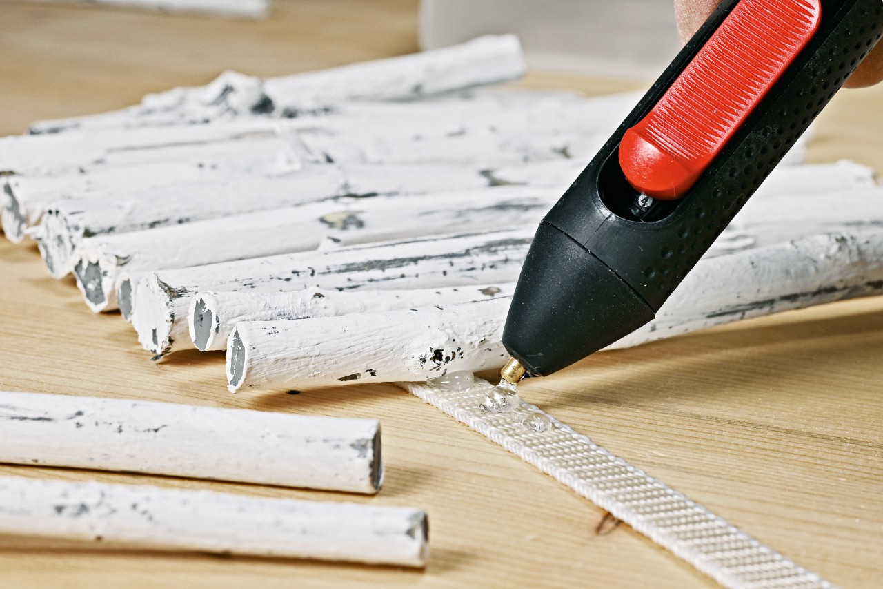 DIY table lamp from twigs: painted branches being stuck to a strap with hot glue
