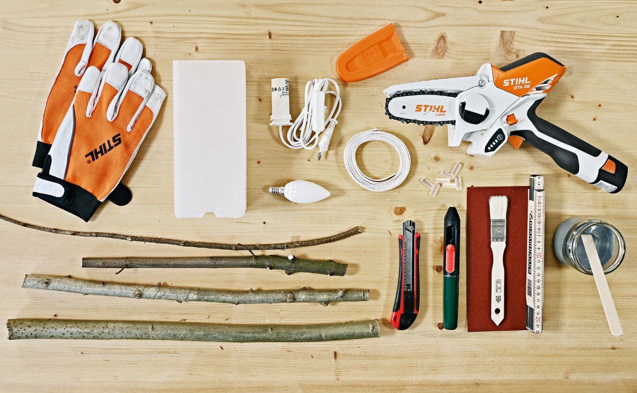 Materials for making a table lamp from twigs: gloves, STIHL GTA 26 cordless garden pruner, branches, and more.