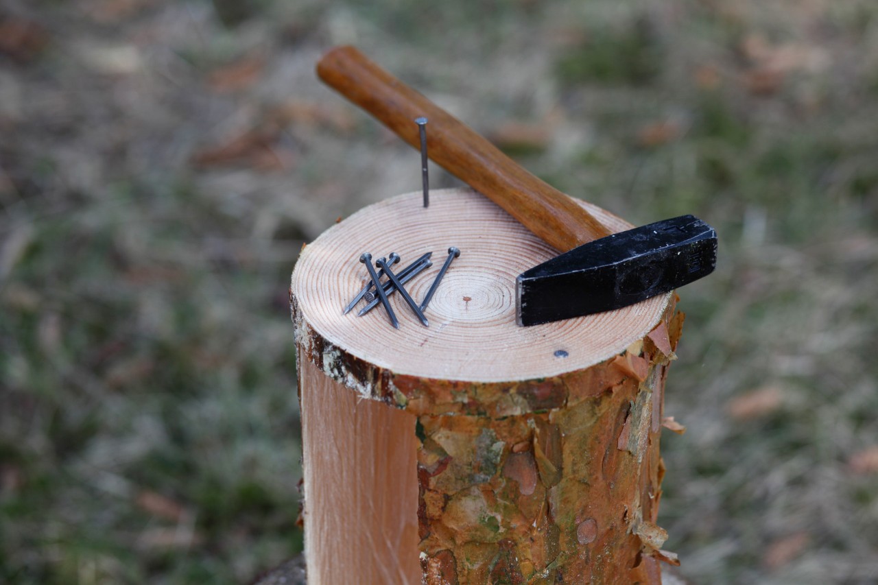  A hammer and nails on an incomplete wooden bird feeder, turned on its side