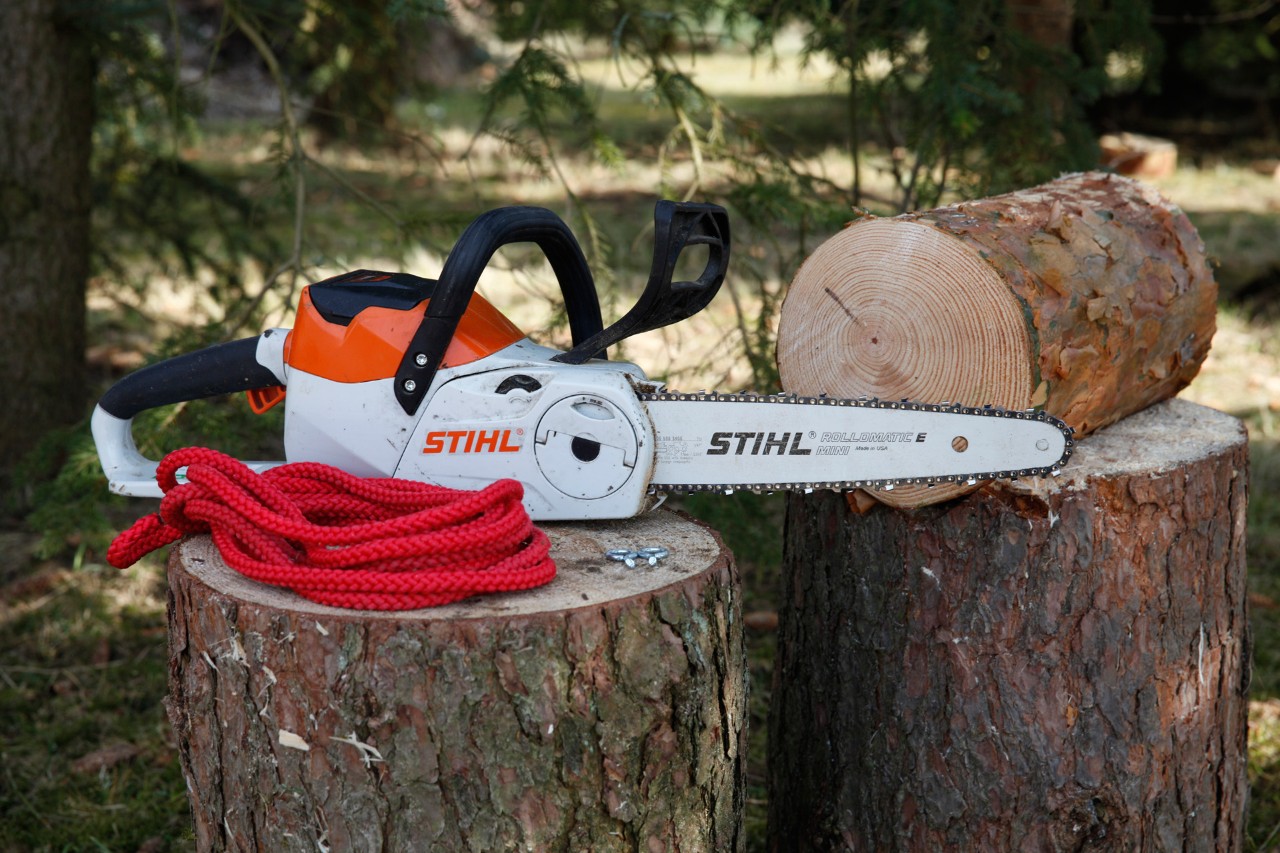 DIY bird feeder: A STIHL MSA 140 C cordless chainsaw, two screw eyes and red cord on a tree trunk