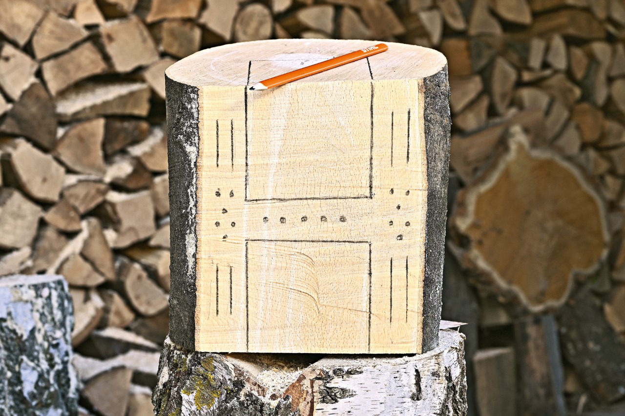 The recesses and holes for a DYI bug hotel are marked on the flat cut face of an upright log 