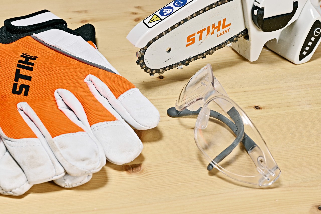 STIHL GTA 26 cordless garden pruner, STIHL safety gloves and glasses on a wooden bench
