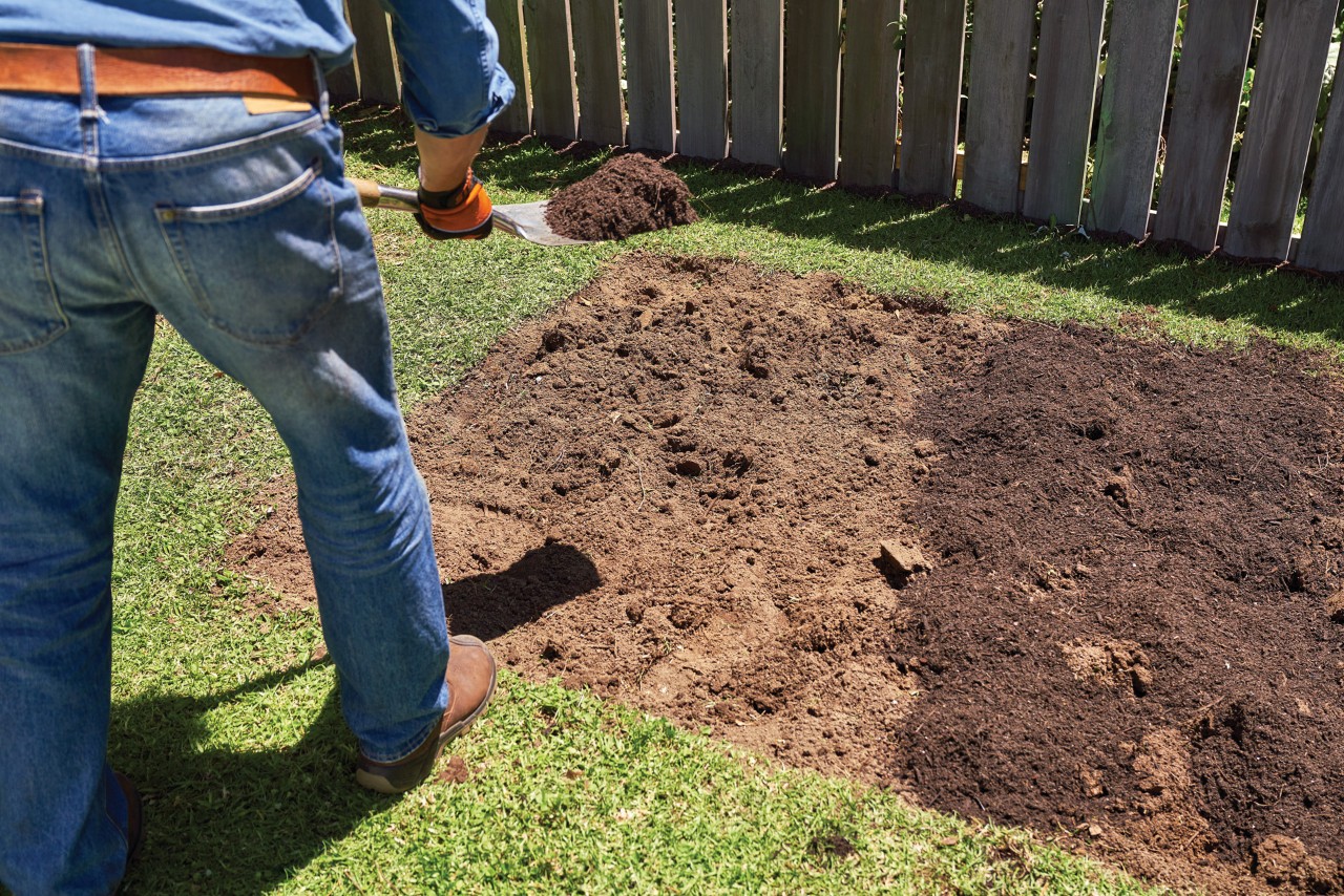 Compost being shovelled into a bed of bare earth