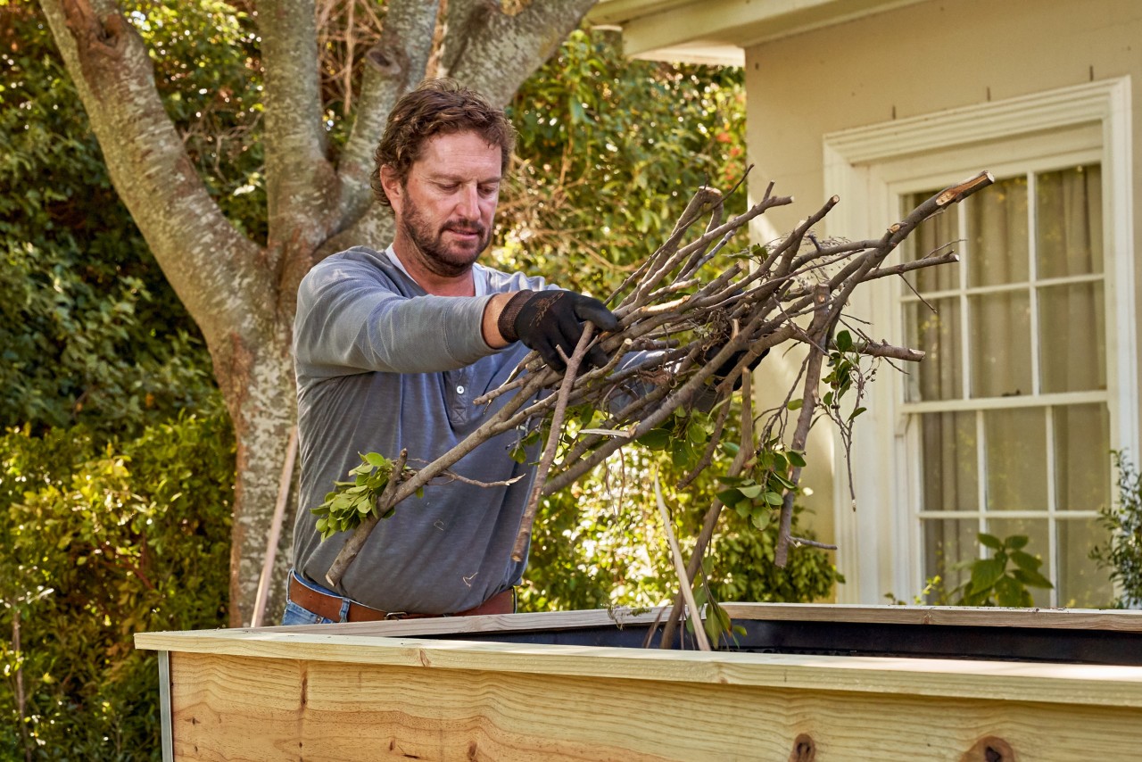 A man putting branches into a raised bed