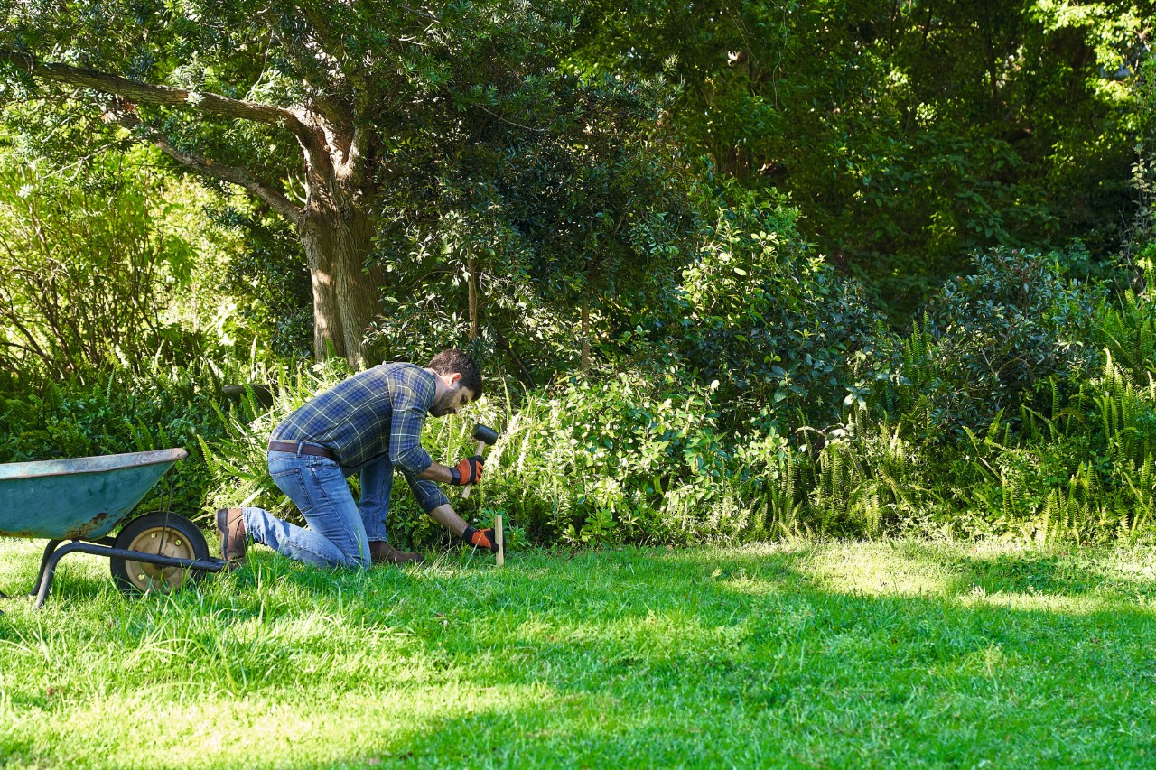 A man marking out the area for creating a wildflower meadow using some washing line and stakes 