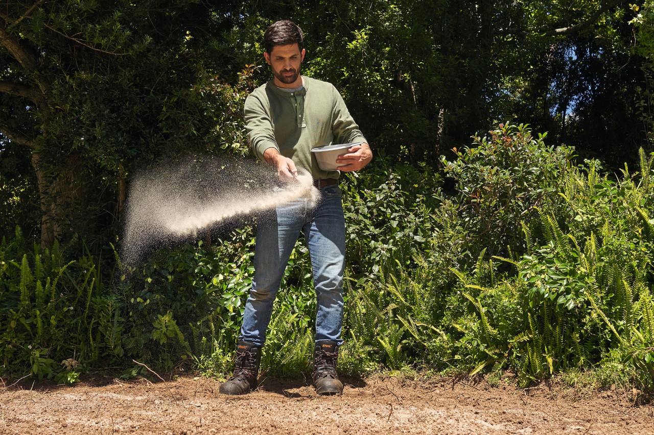 A man spreading seeds to create a wildflower meadow 
