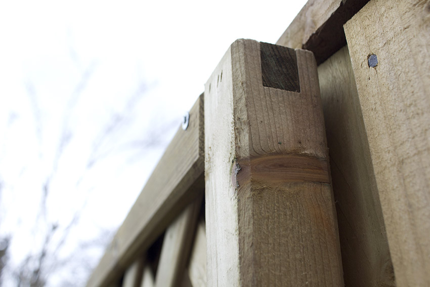close up of top corner of wooden trellis sitting away from the fence