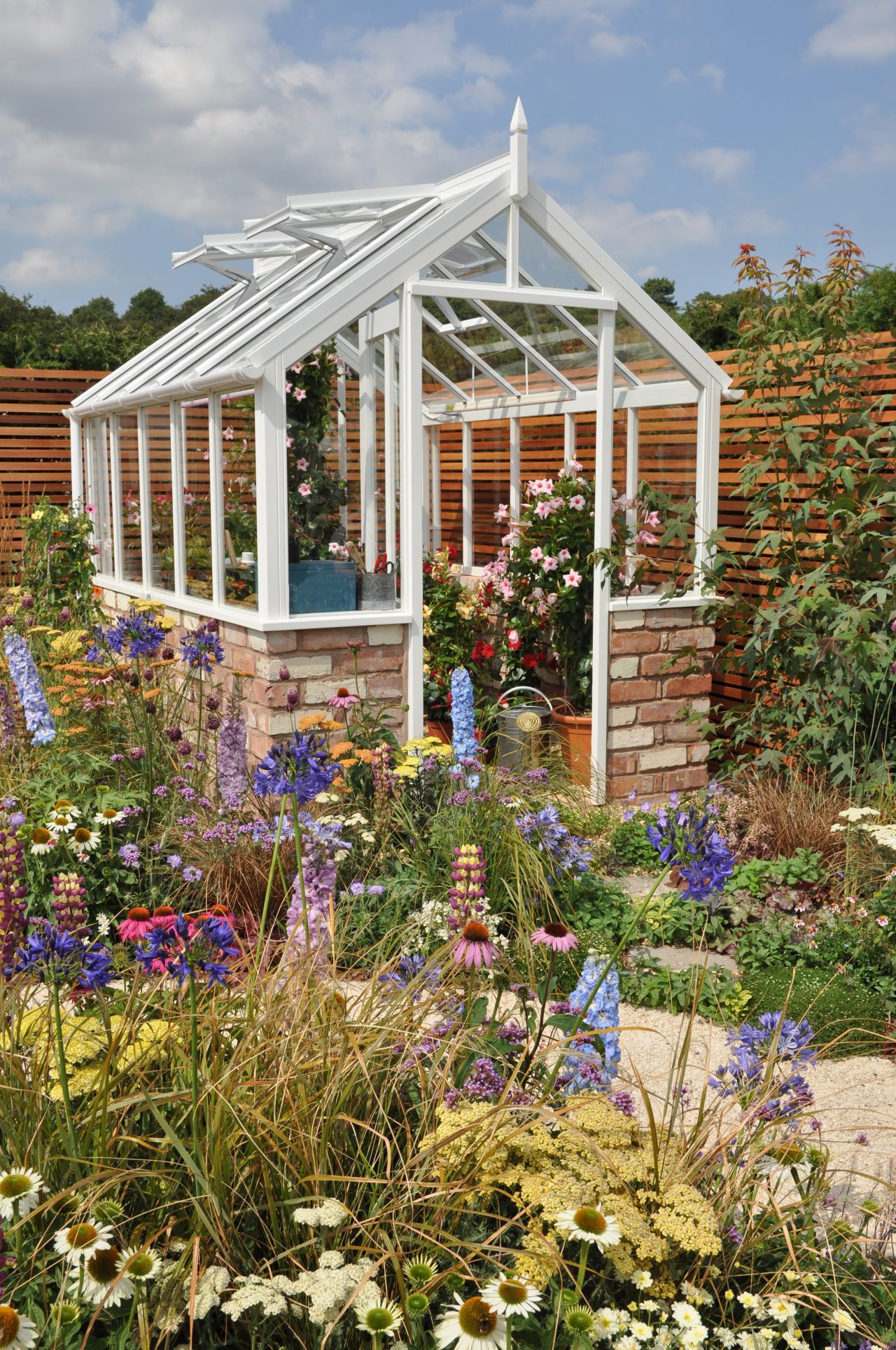 Greenhouse in flowering garden with open vents