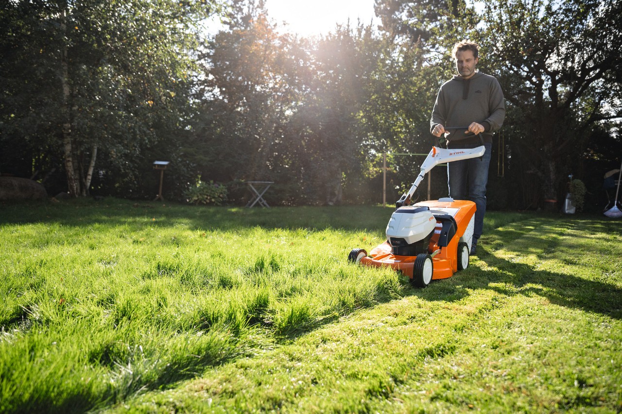 Man mowing the lawn with STIHL lawn mower on sunny day