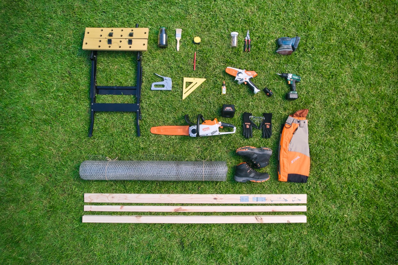 Bird’s-eye view of the materials and tools required to build your own composter, arranged next to each other on grass