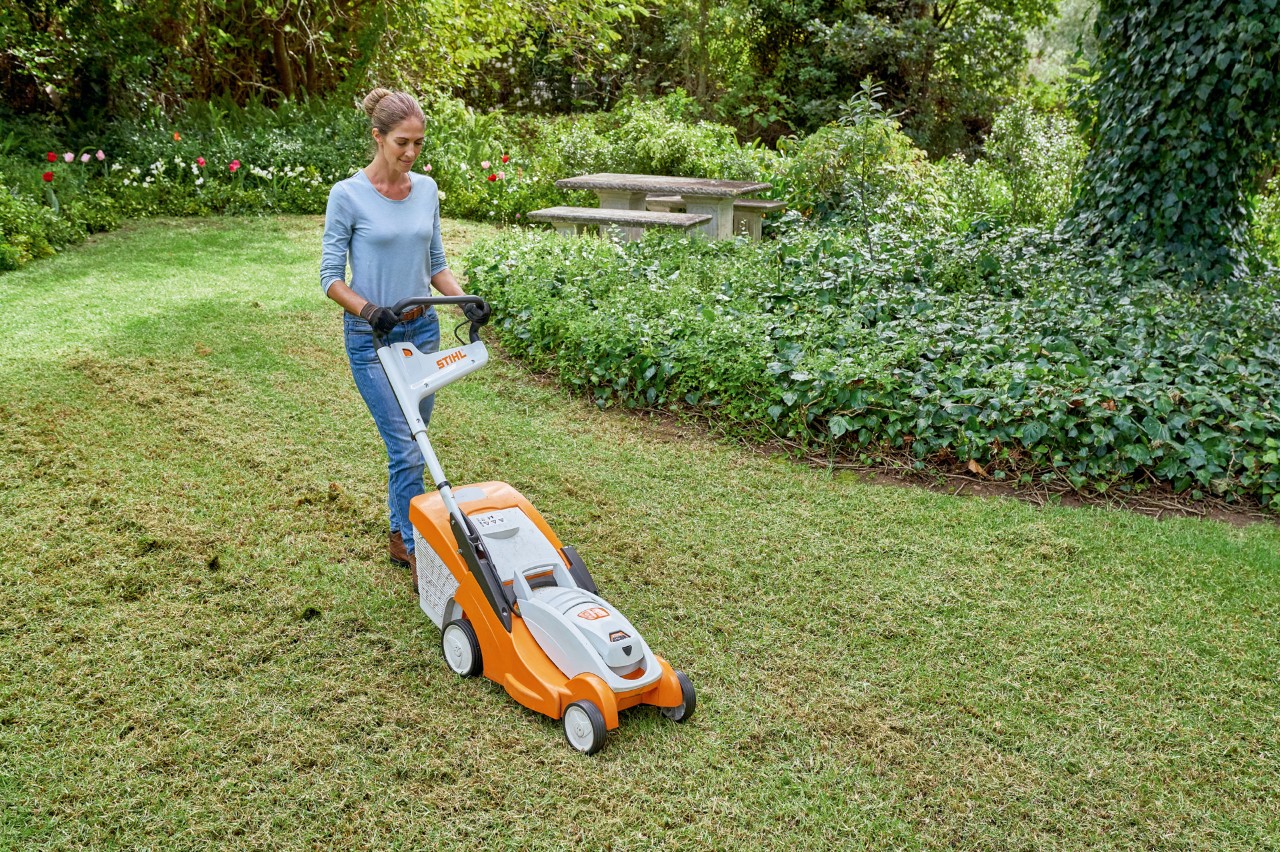 A woman mowing her lawn with a STIHL RMA 339 C cordless lawn mower to prepare it for renewal