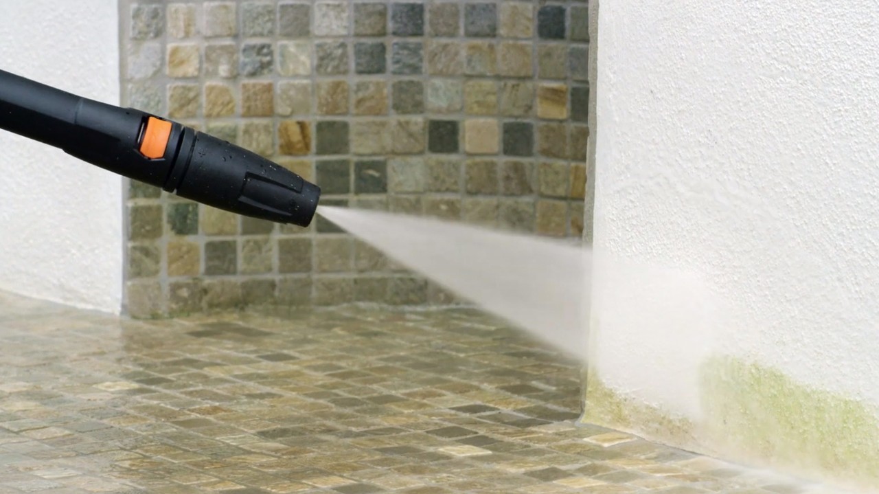 A rendered facade is cleaned with a pressure washer