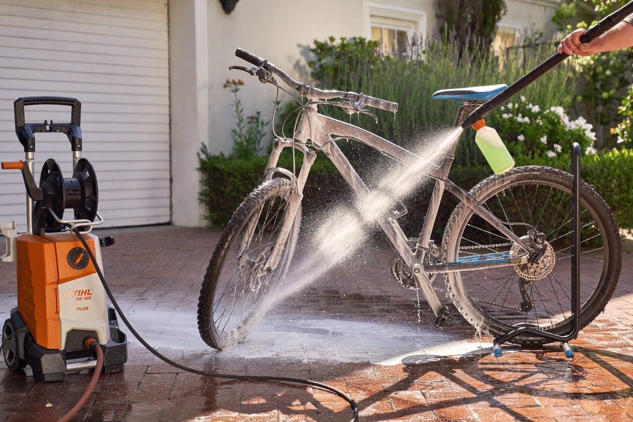 A bike being cleaned with a STIHL RE 130 plus high-pressure cleaner with foam nozzle and vehicle shampoo