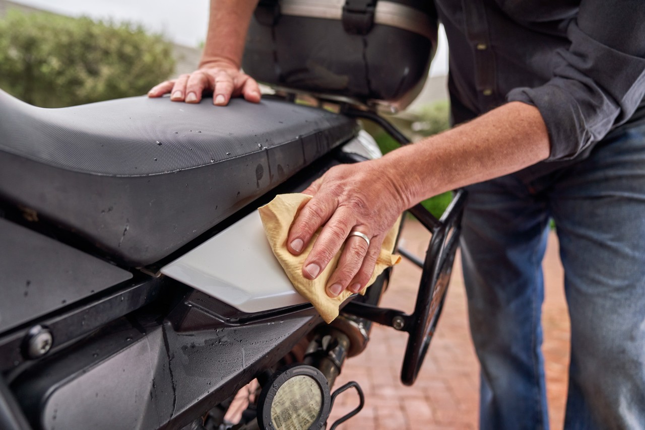 Close-up of wax being applied with a soft cloth to a painted area of a motorcycle 