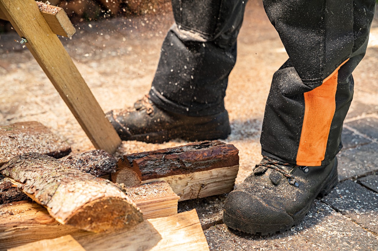 Close-up of safety boots being worn, surrounded by sawdust and some small logs