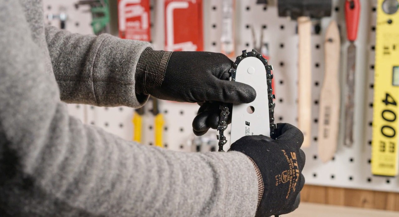 A saw chain being fitted on the guide bar of a STIHL MSA 180 cordless chainsaw