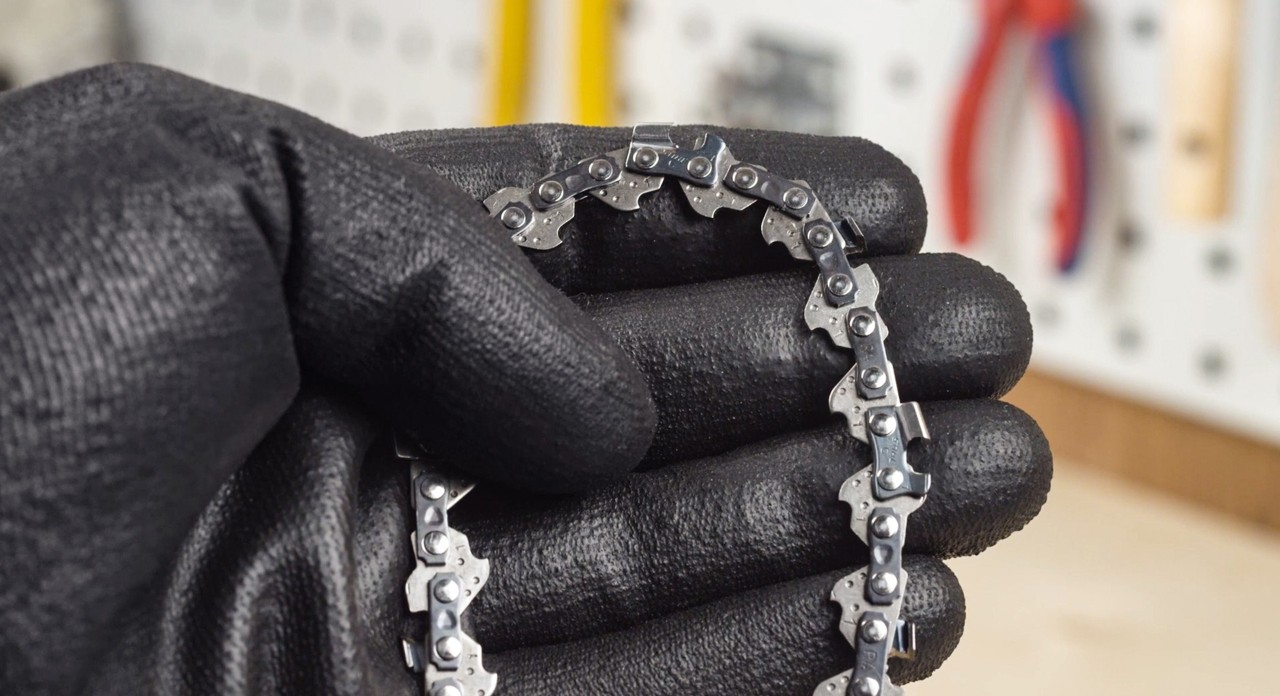 Close-up of a saw chain being held by someone wearing gloves